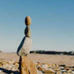 Balanced stones stacked on a sandy beach with clear sky